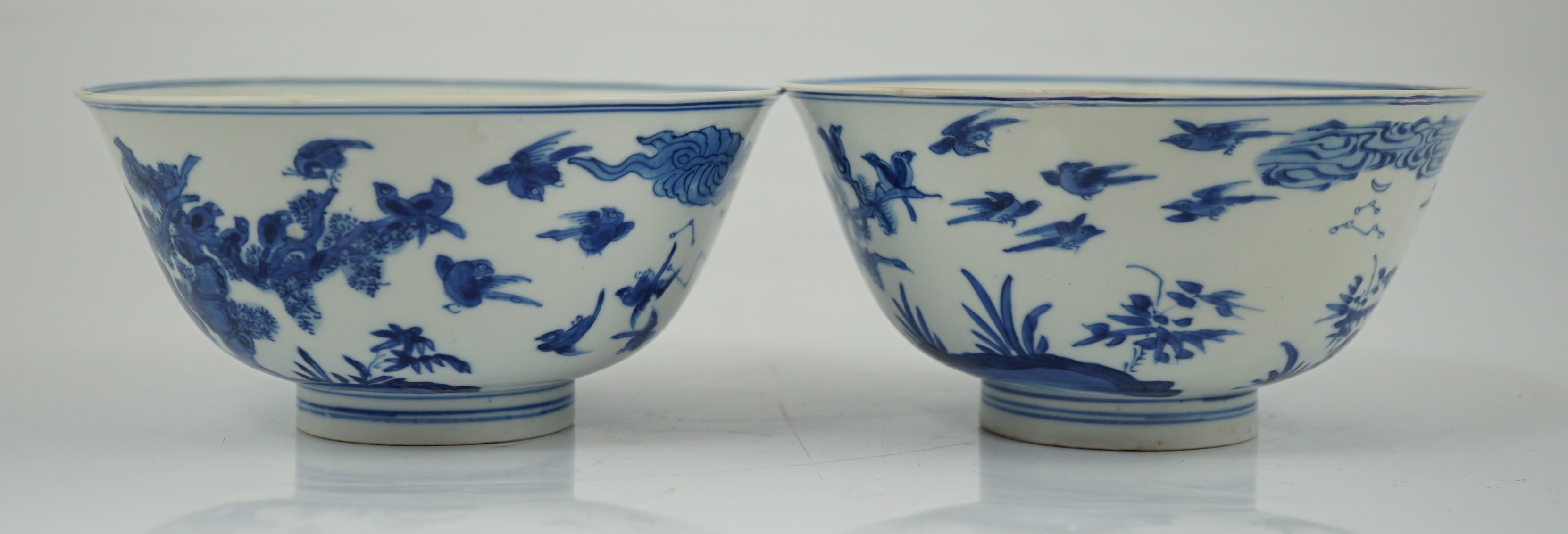 A near pair of Chinese blue and white ‘birds’ bowls, Kangxi period, one bowl restored